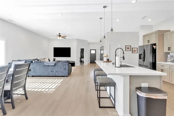 a living room with stainless steel appliances furniture a flat screen tv and kitchen view