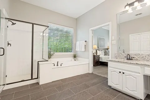 a spacious en suite bathroom with a double vanity sink a mirror and a bathtub