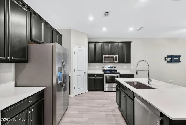 a kitchen with stainless steel appliances granite countertop a refrigerator a stove top oven a sink and dishwasher