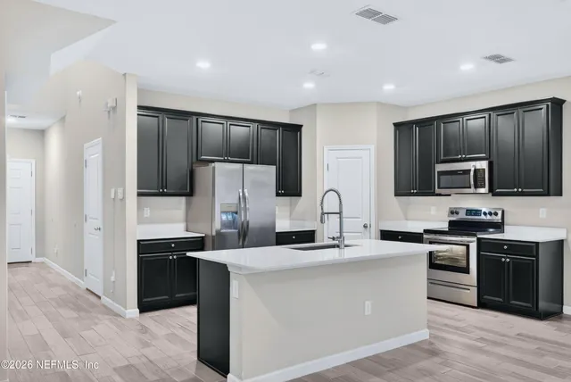 a kitchen with kitchen island a sink stainless steel appliances and cabinets