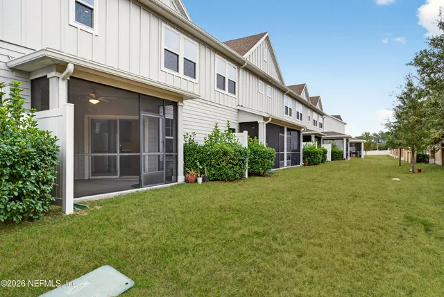 a view of a white house with a yard and potted plants