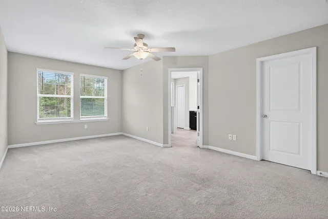 an empty room with windows and fan