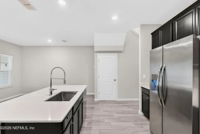 a kitchen with stainless steel appliances kitchen island a refrigerator sink and cabinets