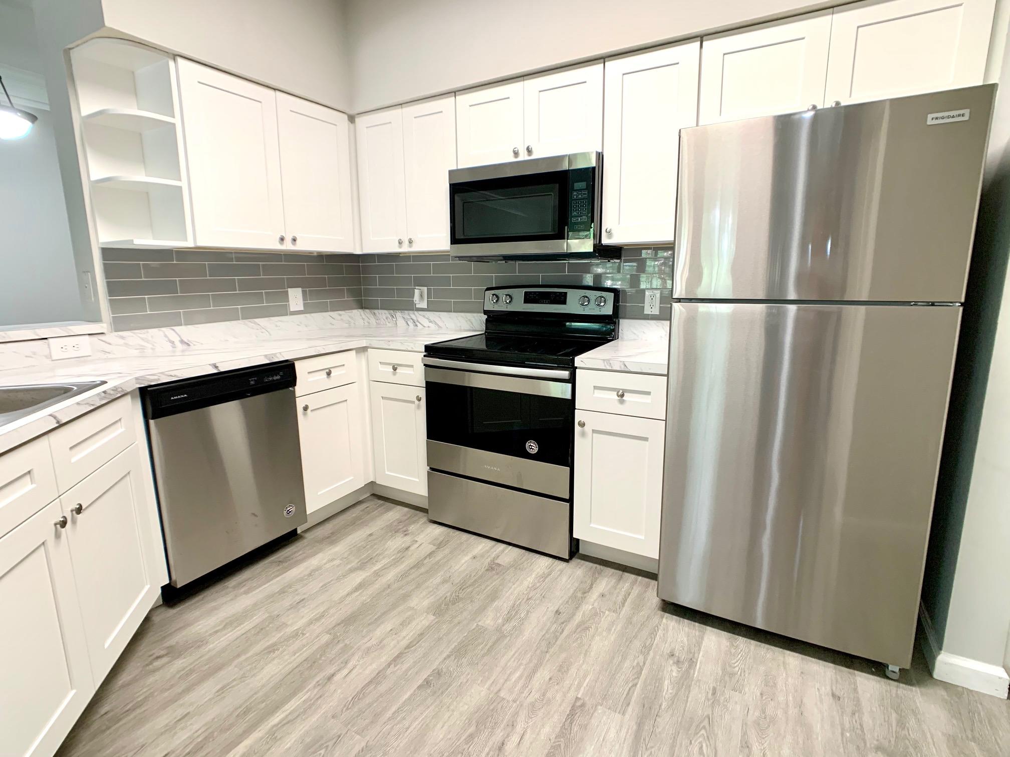 a kitchen with white cabinets stainless steel appliances and wooden floor