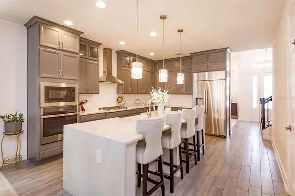 a kitchen with stainless steel appliances a refrigerator a stove microwave and white cabinets with wooden floor