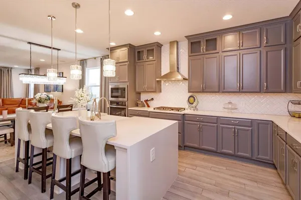 a kitchen with stainless steel appliances granite countertop a sink a stove a refrigerator and island with wooden floor