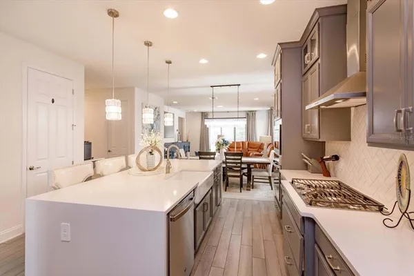 a kitchen with a stove a sink dishwasher and a refrigerator with wooden floor