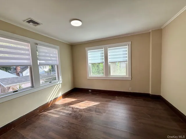 a view of an empty room with a window and wooden floor