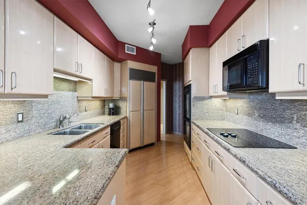a kitchen with stainless steel appliances granite countertop a sink refrigerator and cabinets