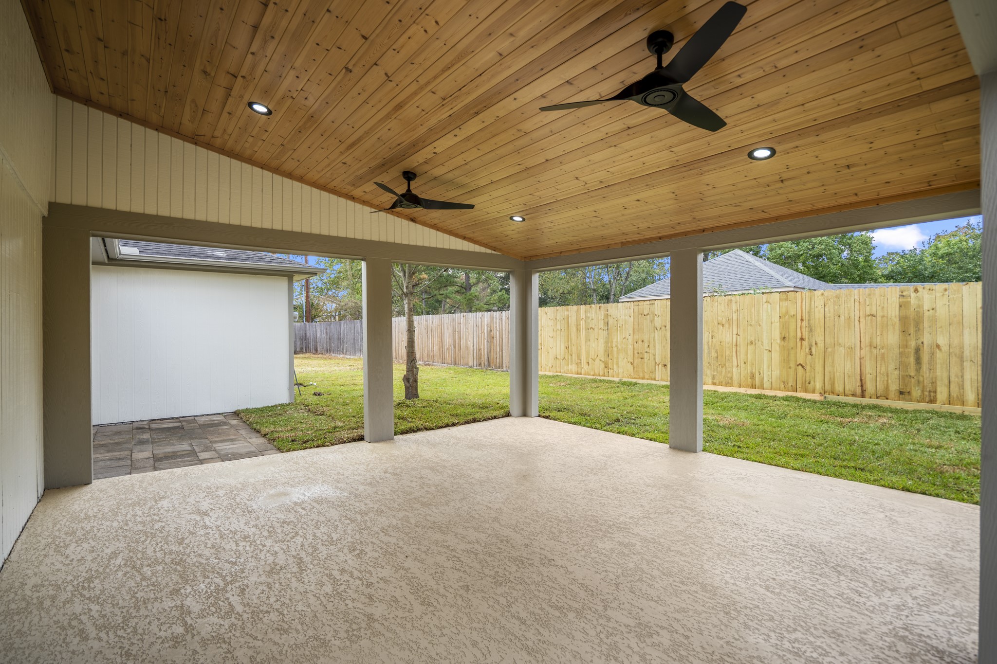 8006 Vickridge Lane Spring, TX 77379 - Photo 41 of 50 The covered patio was refreshed in 2025 and offers a generous outdoor living area with a wood-paneled ceiling, recessed lighting, and dual ceiling fans. It’s the perfect spot for relaxing, gathering, or enjoying the large backyard year-round.