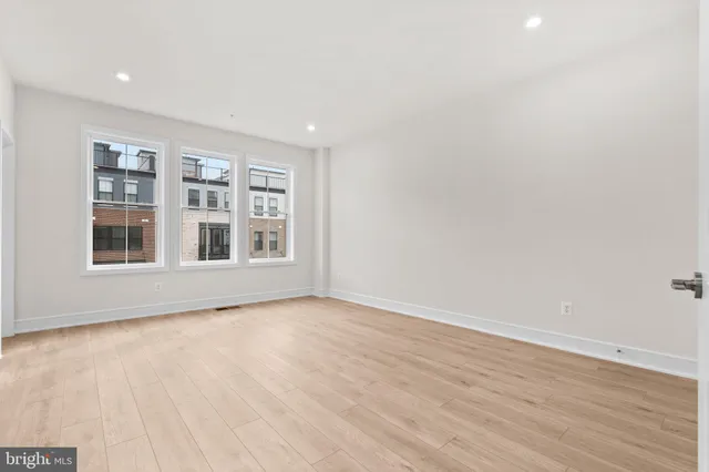 a view of an empty room with wooden floor and window