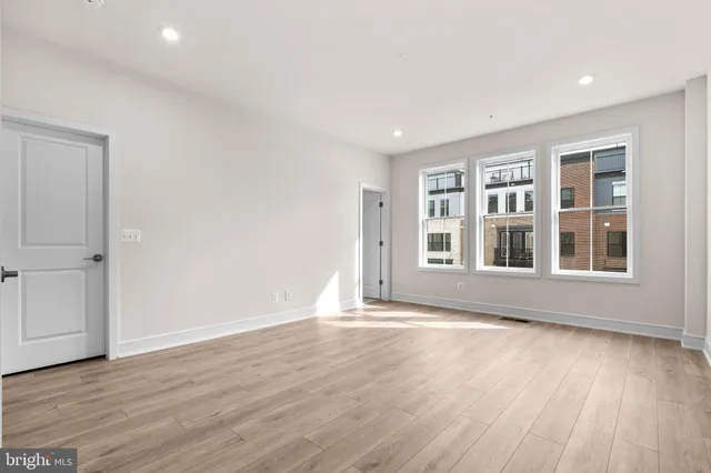 a view of an empty room with wooden floor and windows