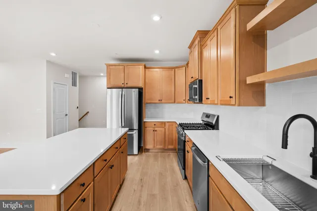 a kitchen with a sink a counter top space stainless steel appliances and cabinets