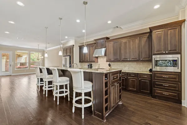 a kitchen with stainless steel appliances granite countertop wooden cabinets a stove a sink and a center island