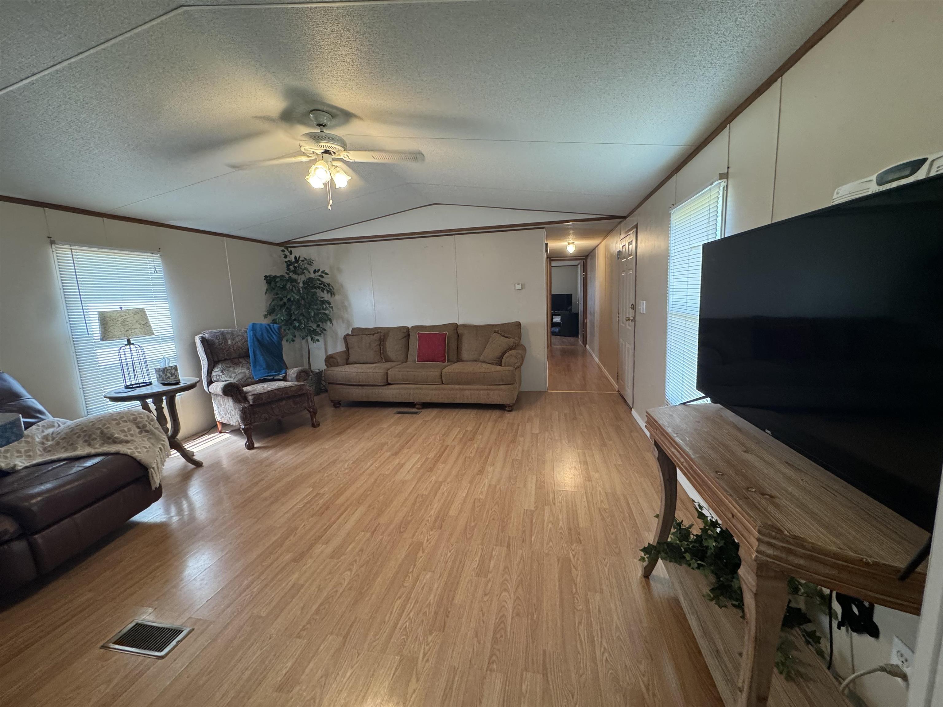 2511 Watkins Road Michie, TN 38357 - Photo 21 of 40 Open-concept living space featuring wood-finish flooring, a ceiling fan with integrated lighting, and multiple windows with blinds