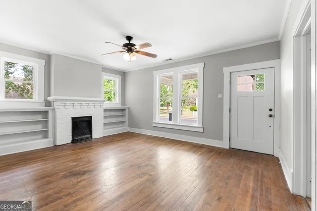 an empty room with windows fireplace and wooden floor