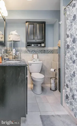 a bathroom with a granite countertop toilet a sink and a mirror