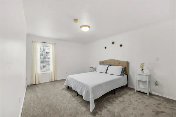 a bed sitting in a spacious bedroom next to a window