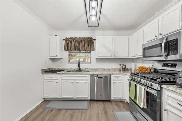 a kitchen with stainless steel appliances white cabinets a sink and a stove
