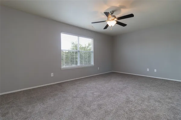 an empty room with ceiling fan and window
