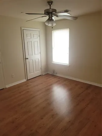 an empty room with wooden floor chandelier fan and windows