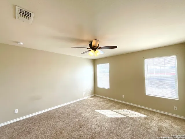 a view of an empty room and window and ceiling fan