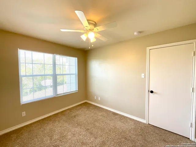 an empty room with a window and a fan