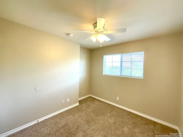 an empty room with a window and ceiling fan