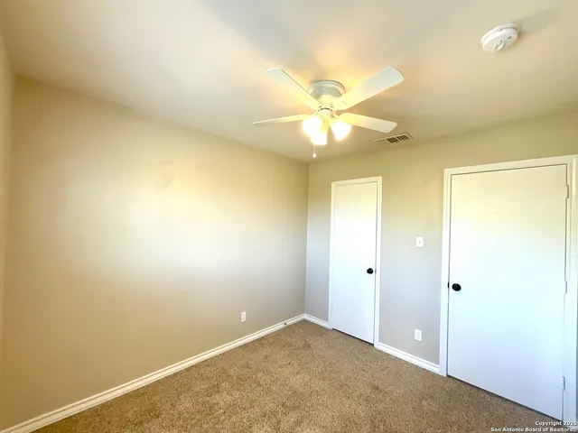 an empty room with a ceiling fan and a window