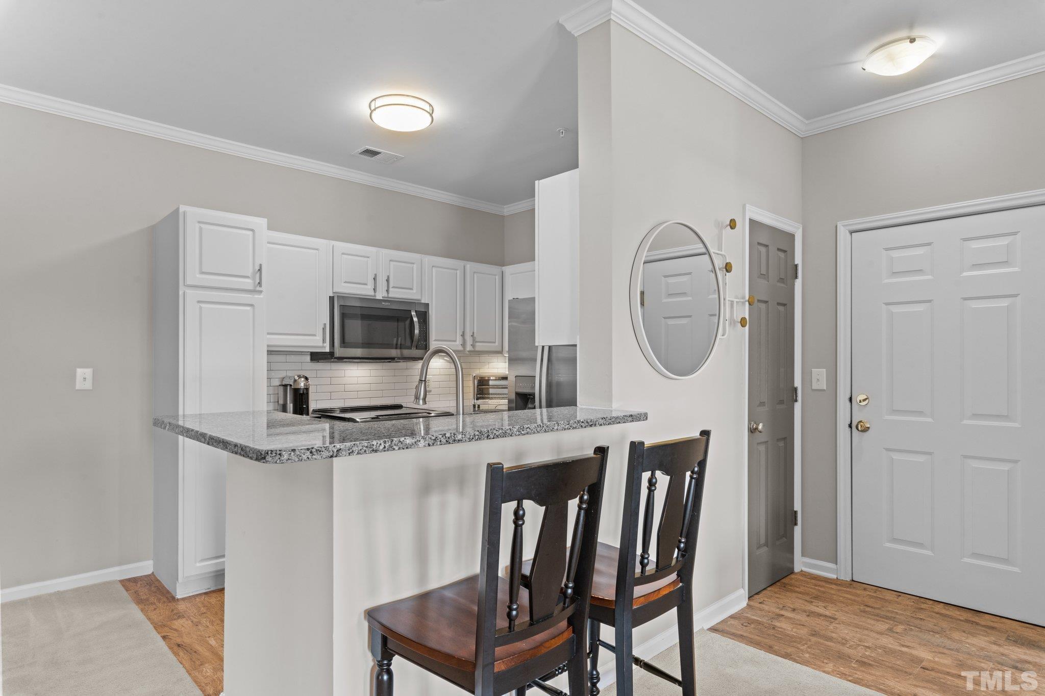 710 North Person Street, Unit 202 Raleigh, NC 27604 - Photo 8 of 33 a kitchen with stainless steel appliances granite countertop a microwave a stove a dining table and chairs with wooden floor