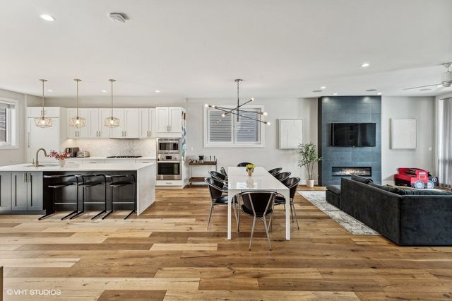 a living room with stainless steel appliances kitchen island granite countertop a dining table and chairs with wooden floor
