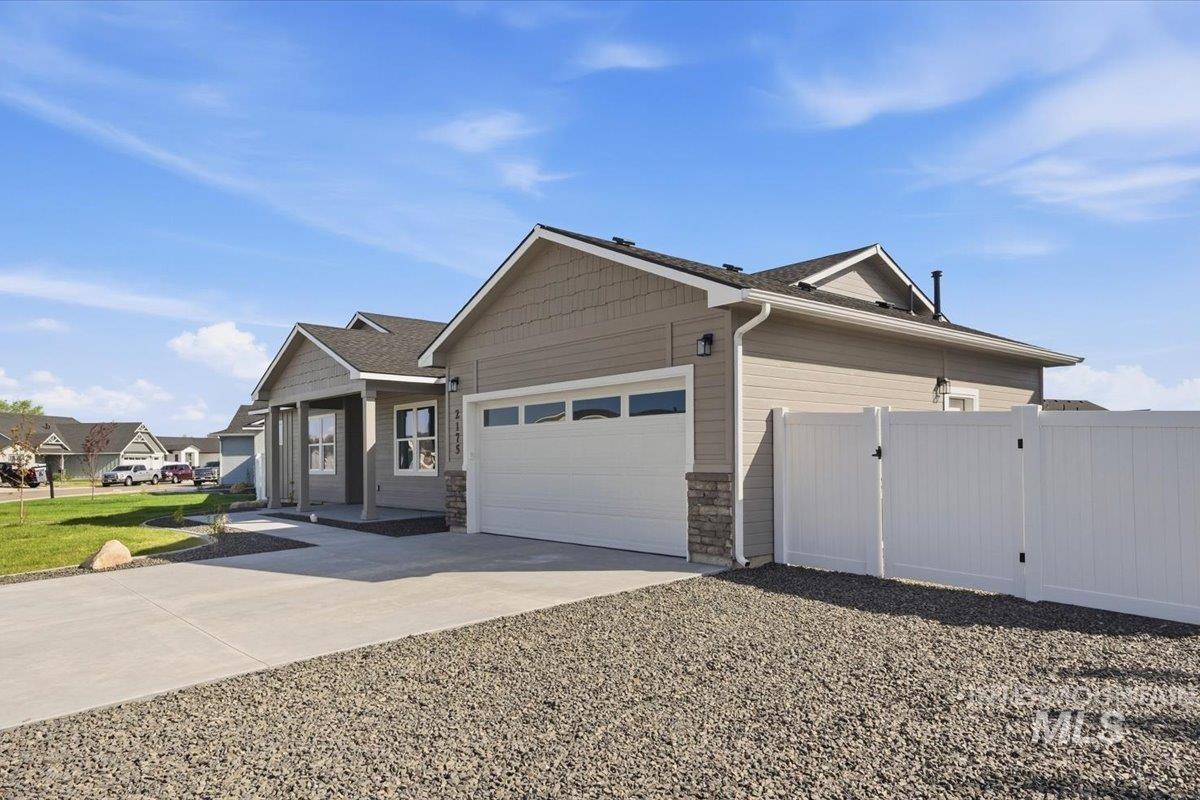 2175 Austin Way Fruitland, ID 83619 - Photo 3 of 30 View of property exterior featuring a gate, driveway, an attached garage, and stone siding