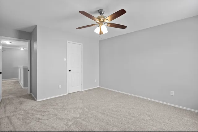 an empty room with closet and a ceiling fan