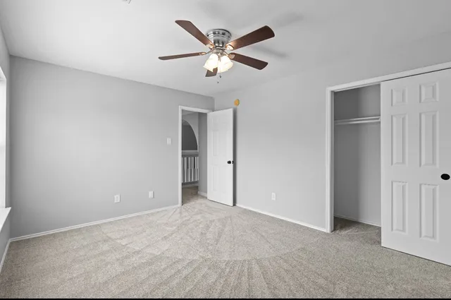 an empty room with closet and ceiling fan