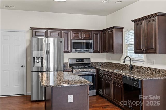 a kitchen with granite countertop a sink stove and refrigerator