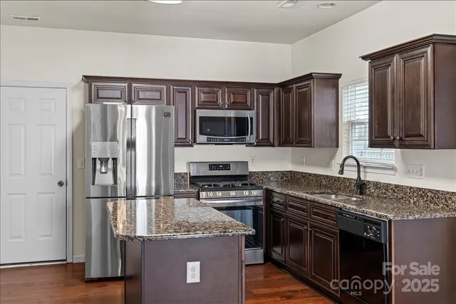 a kitchen with granite countertop a sink stove and refrigerator