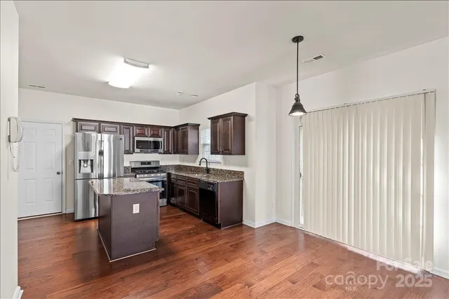 a kitchen with stainless steel appliances granite countertop a refrigerator a stove top oven a sink dishwasher and wooden floor