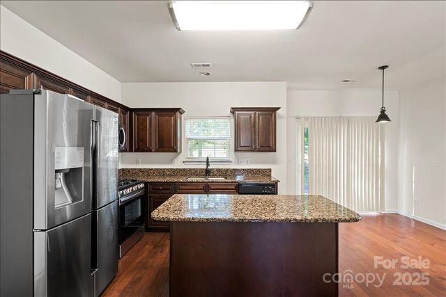 a kitchen with stainless steel appliances granite countertop a refrigerator a stove and a sink