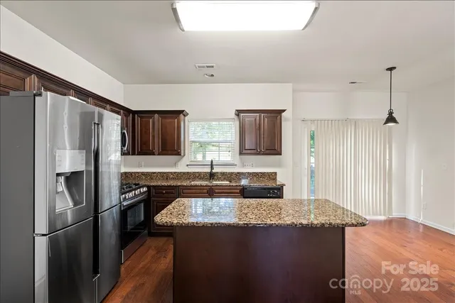 a kitchen with stainless steel appliances granite countertop a refrigerator a stove and a sink
