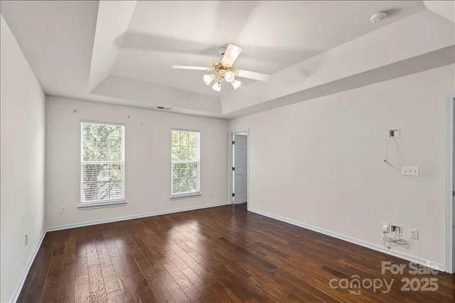 an empty room with wooden floor ceiling fan and windows