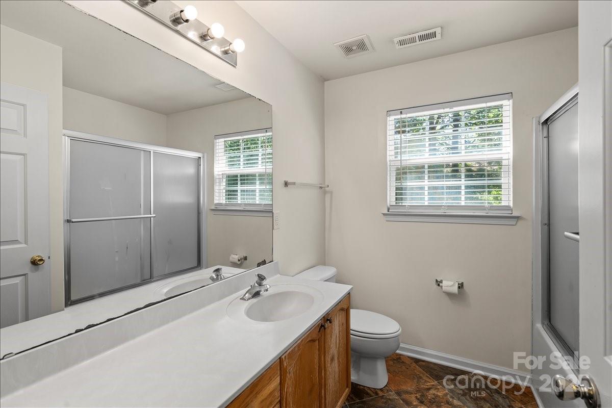 11938 Harmon Lane Pineville, NC 28134 - Photo 28 of 36 a bathroom with a toilet a sink a mirror a vanity and window