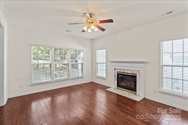 an empty room with windows fireplace and a ceiling fan
