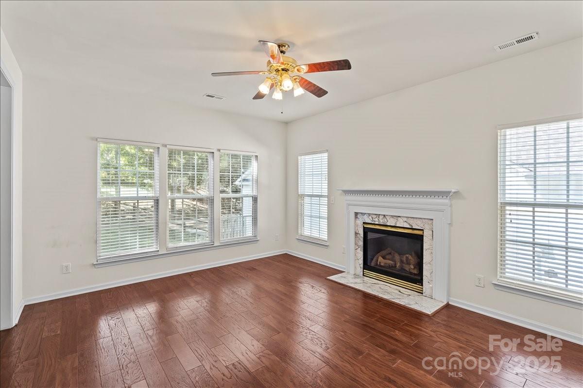 11938 Harmon Lane Pineville, NC 28134 - Photo 10 of 36 an empty room with windows fireplace and a ceiling fan