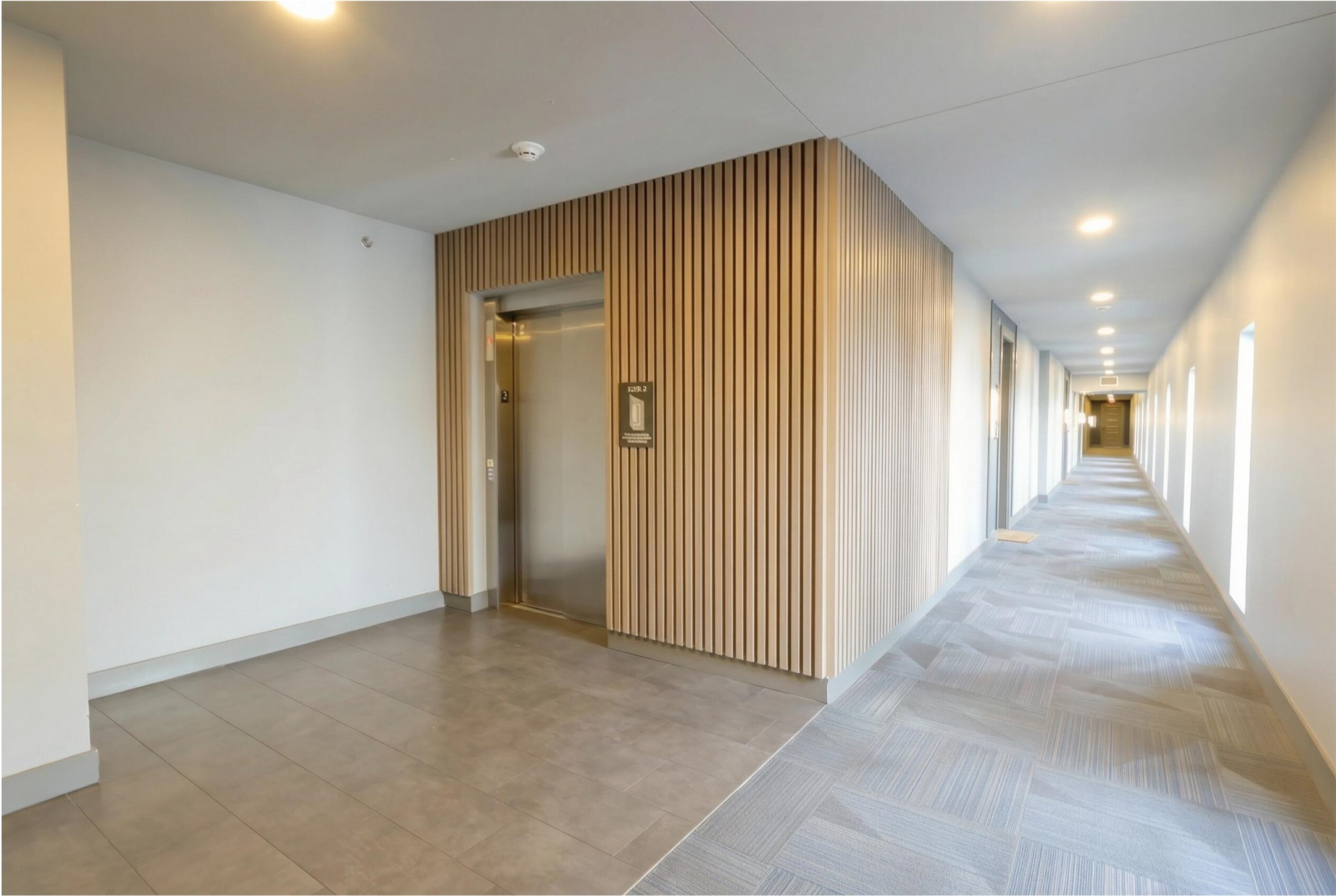 2220 Webberville Road, Unit 303 Austin, TX 78702 - Photo 4 of 14 Hallway with recessed lighting, elevator, and wooden walls