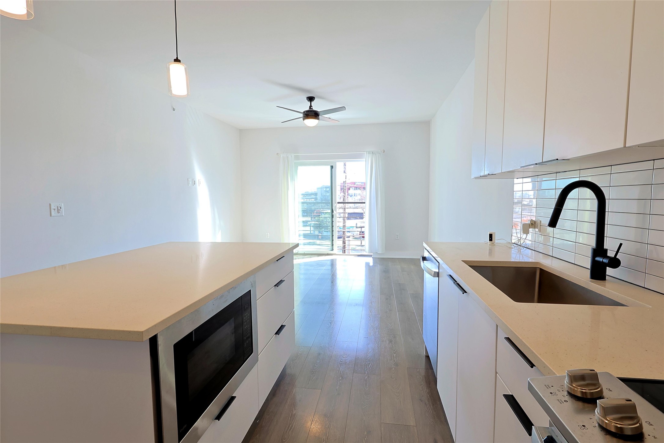 2220 Webberville Road, Unit 303 Austin, TX 78702 - Photo 6 of 14 Kitchen featuring modern cabinets, hanging light fixtures, white cabinets, appliances with stainless steel finishes, and dark wood-style flooring