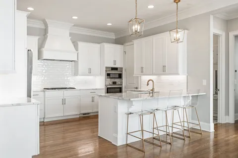 a open kitchen with kitchen island white cabinets and stainless steel appliances