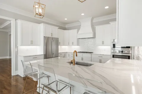 a kitchen with stainless steel appliances kitchen island granite countertop a sink refrigerator and cabinets