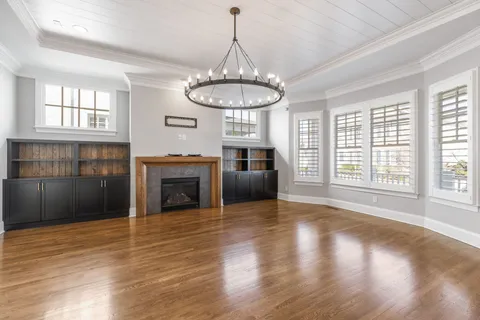 a view of a livingroom with a fireplace wooden floor and windows