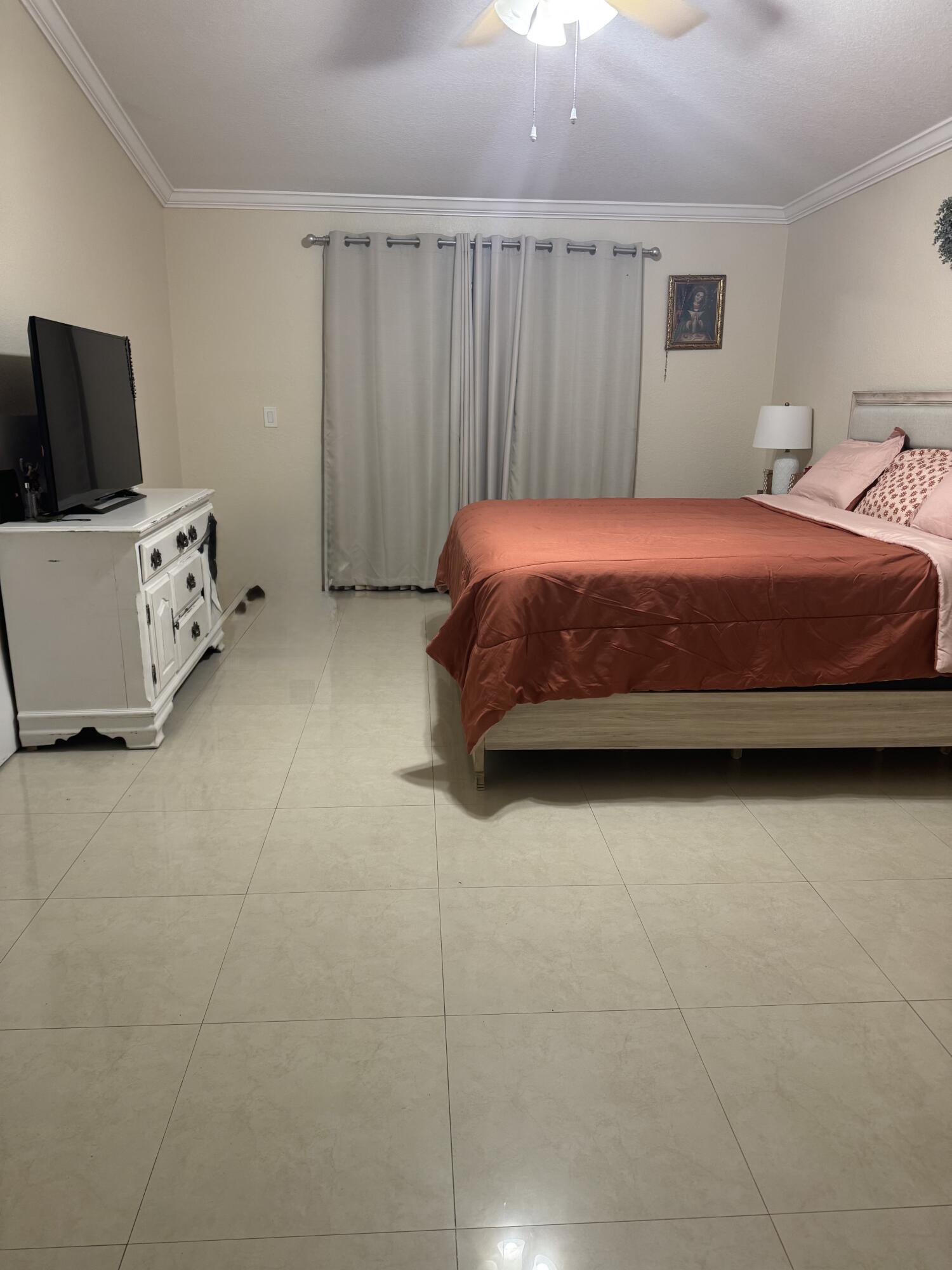 5621 Azalea Circle West Palm Beach, FL 33415 - Photo 16 of 20 a bedroom with a bed and flat tv screen on the dresser