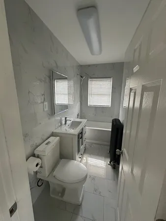 a bathroom with a toilet a sink a desk and chair